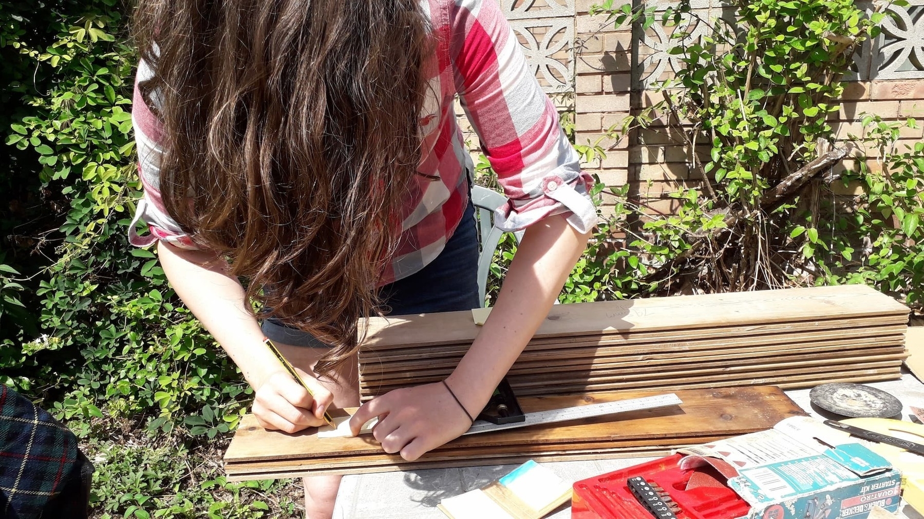 A picture of me measuring planks of wood and labelling them