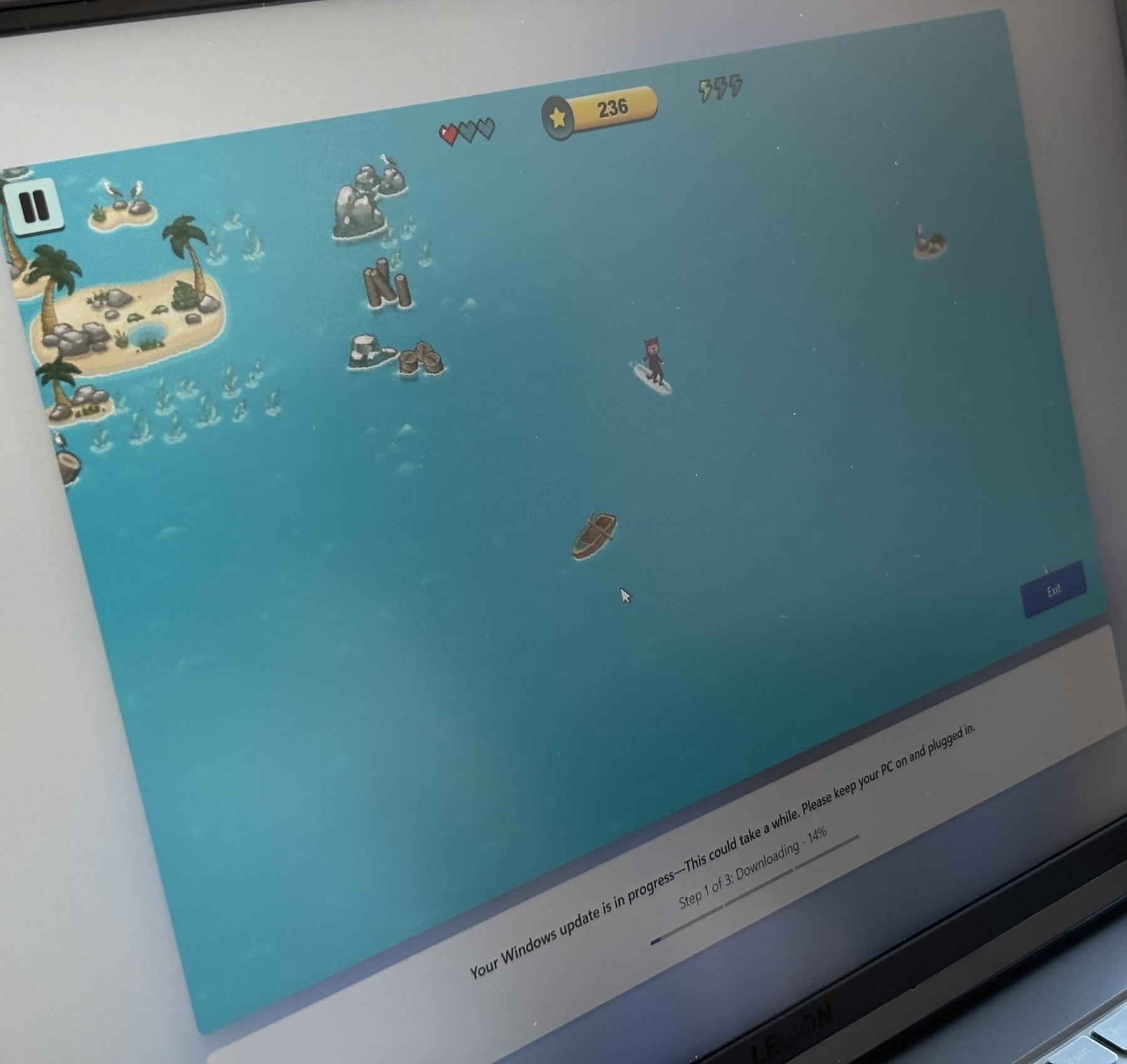 A computer screen displays an ocean-themed video game with islands, boats, and a user interface, while a Windows update notification is visible at the bottom.