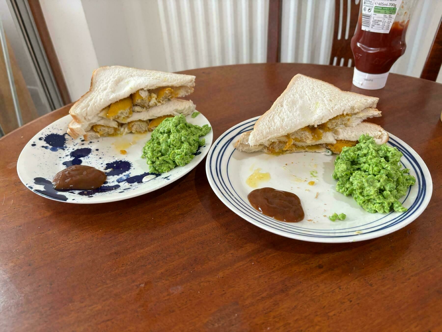 Two vegetarian fish finger sandwiches that are well presented with visible curry sauce and mushy peas