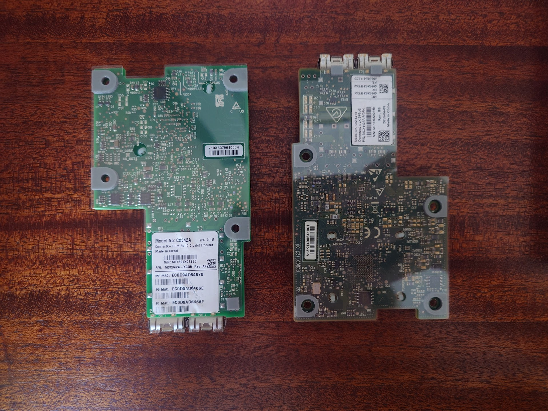 Two electronic circuit boards with various components and labels are placed side by side on a wooden surface.